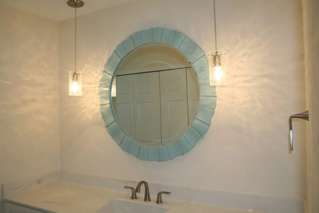Bathroom vanity with a pale blue mirror and pendant lighting